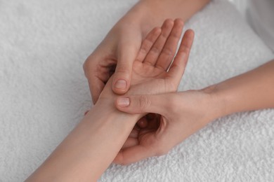 Photo of Woman receiving hand massage on soft towel, closeup