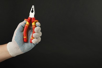 Photo of Man with combination pliers on black background, closeup. Space for text