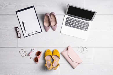 Flat lay composition with business supplies and fashionable accessories on white wooden floor. Concept of balance between work and life