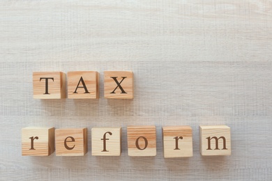 Cubes on wooden background, top view. Tax concept