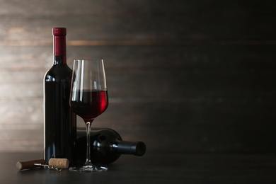 Composition with glass and bottles of red wine on table. Space for text