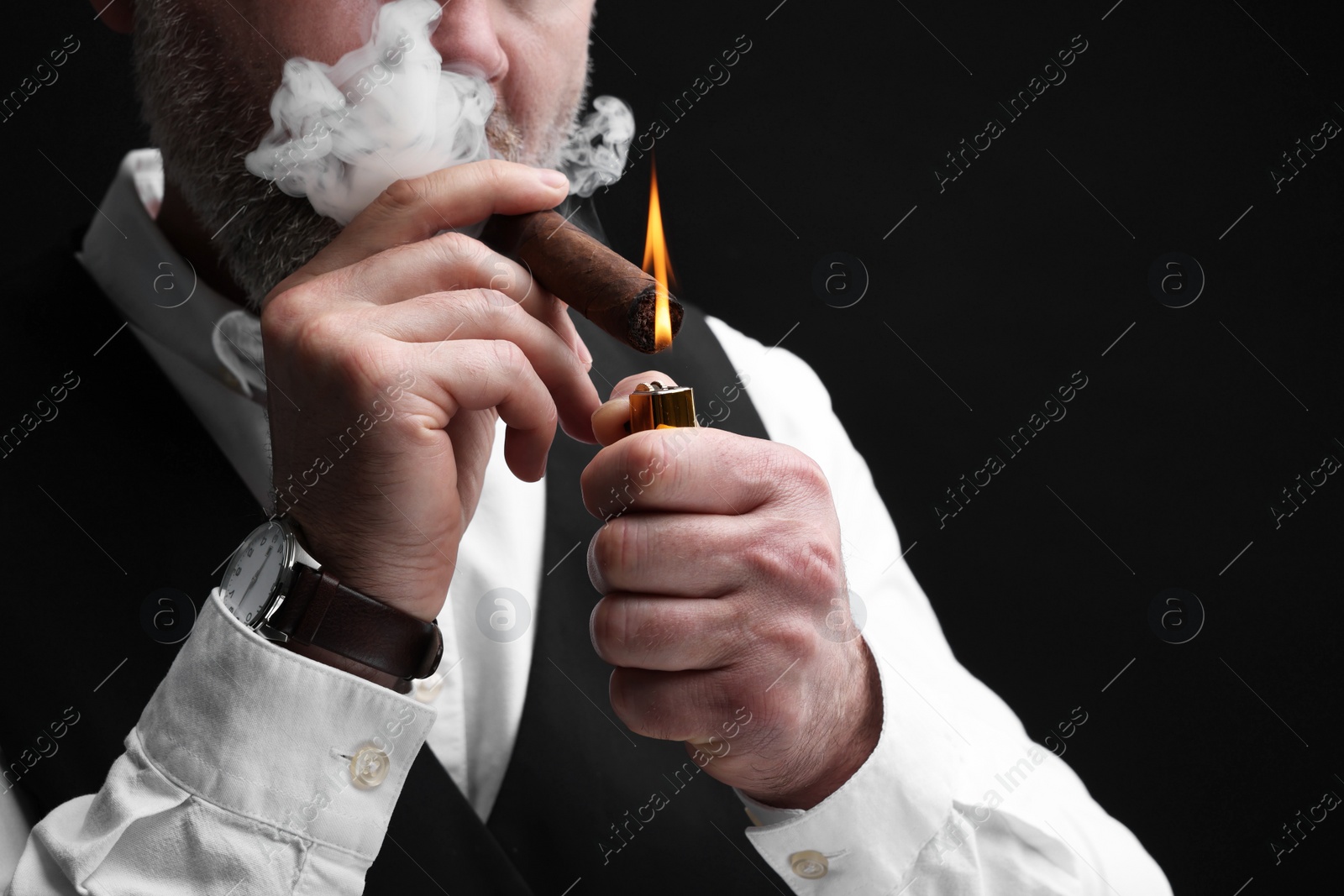 Photo of Man lighting cigar on black background, closeup. Space for text