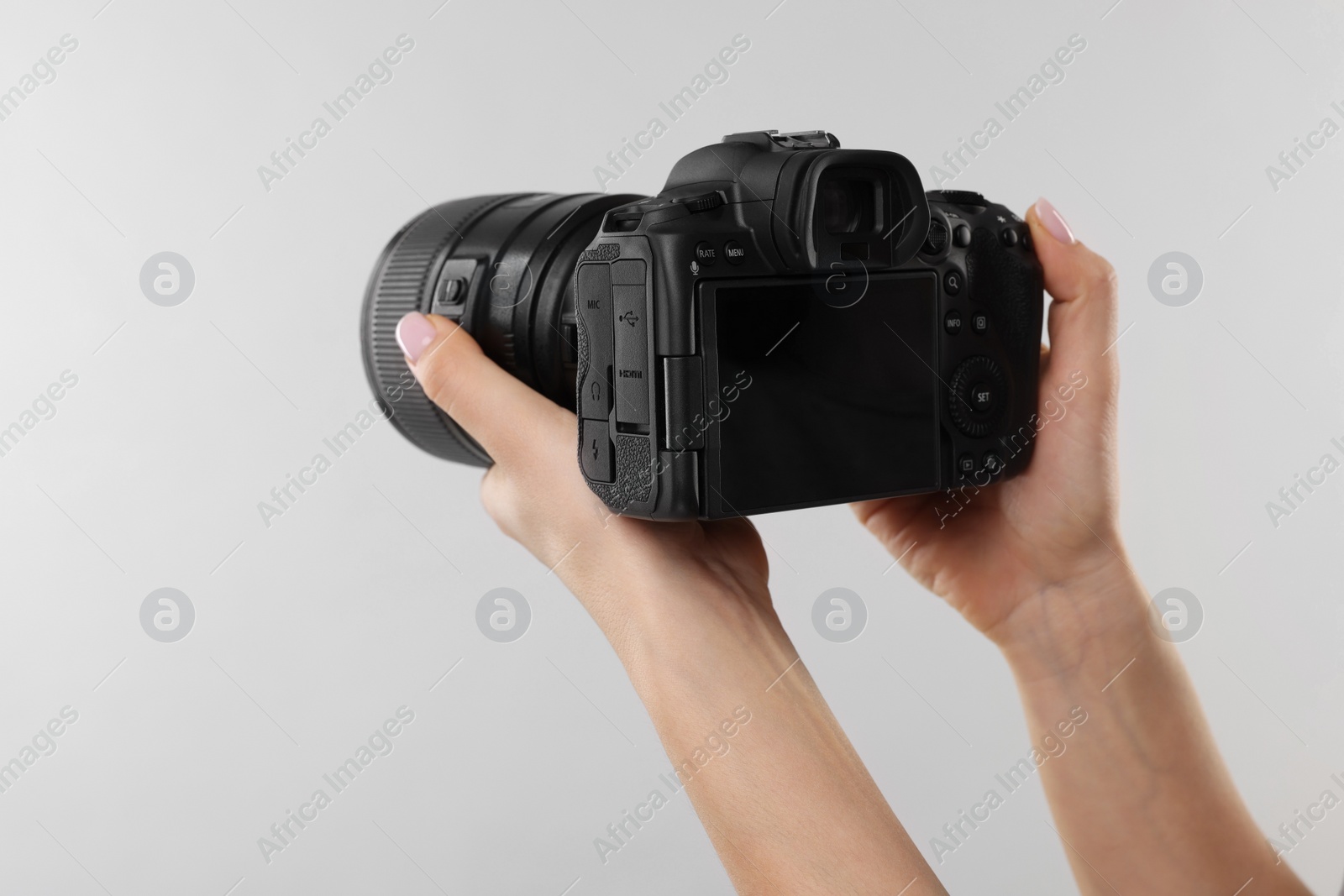 Photo of Photographer with camera on light grey background, closeup