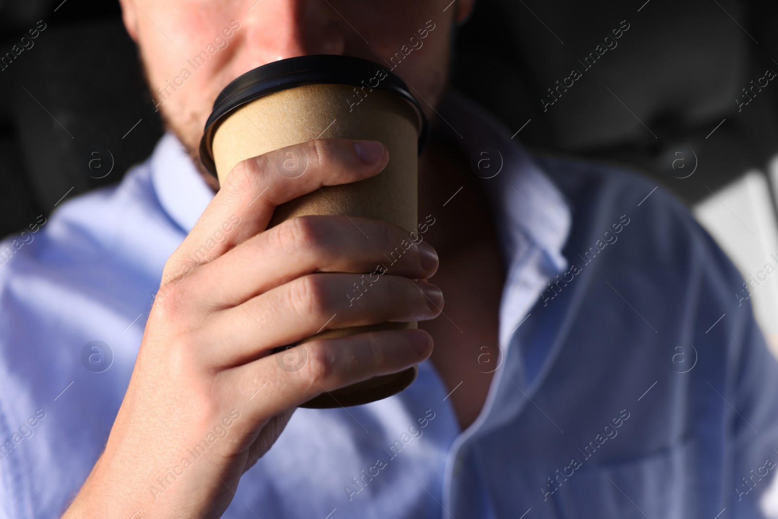 Photo of To-go drink. Man drinking coffee in car, closeup