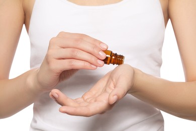 Photo of Young woman applying essential oil onto wrist on white background, closeup