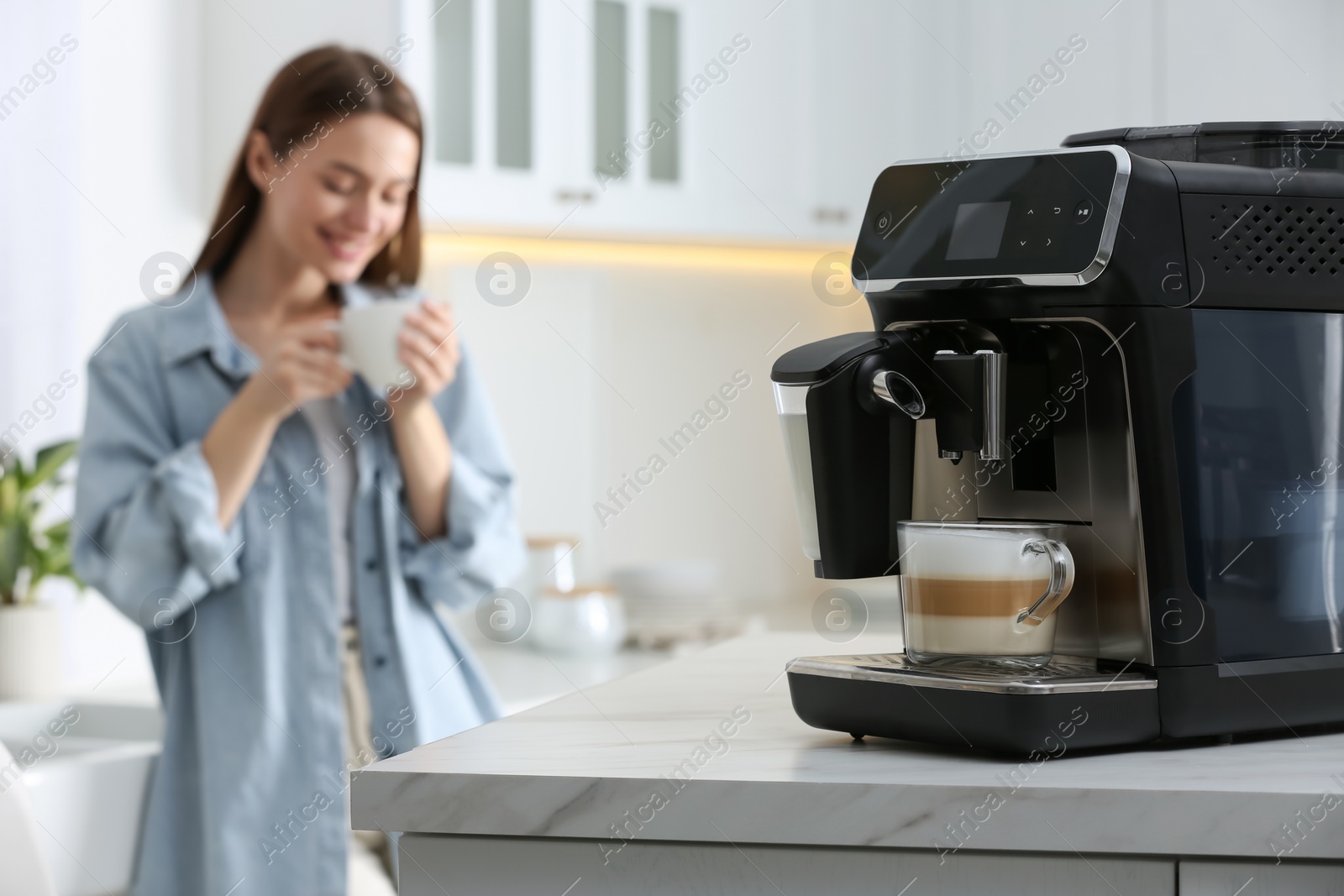 Photo of Young woman enjoying fresh aromatic coffee in kitchen, focus on modern machine