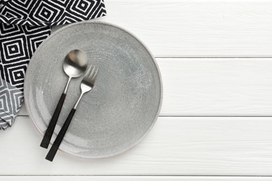 Photo of Stylish setting with cutlery, napkin and plate on white wooden table, top view. Space for text