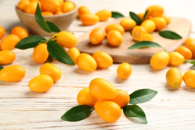 Fresh ripe kumquats and leaves on white wooden table