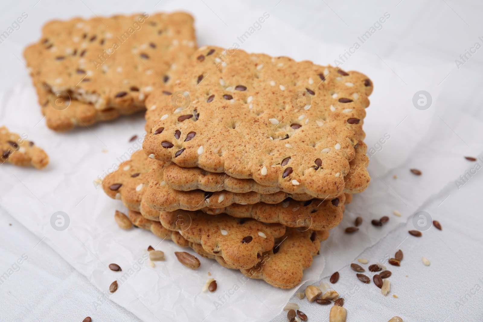 Photo of Stack of cereal crackers with flax and sesame seeds on white tiled table, closeup