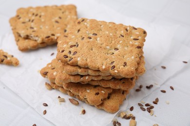 Photo of Stack of cereal crackers with flax and sesame seeds on white tiled table, closeup