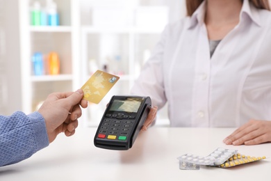 Client using credit card for terminal payment in pharmacy, closeup