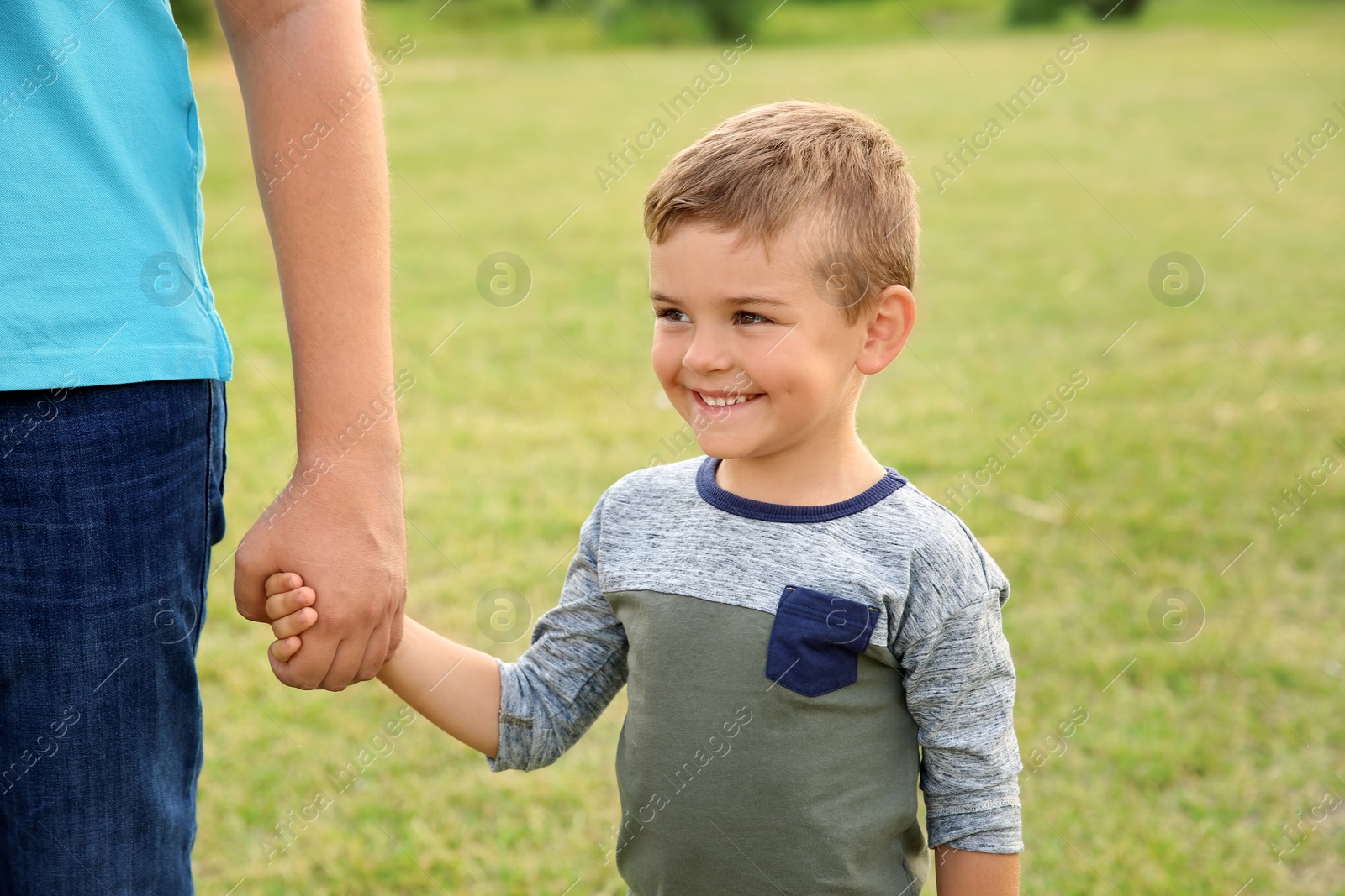 Photo of Man holding hands with his child outdoors. Happy family