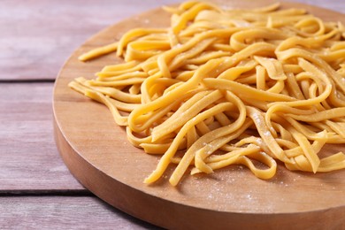 Photo of Board with homemade pasta on wooden table, closeup