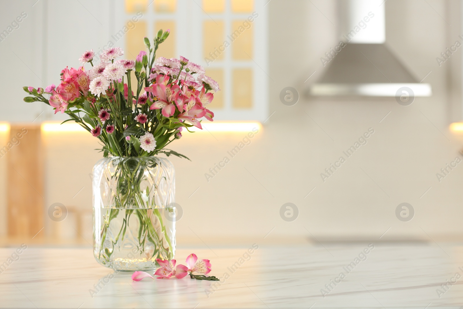 Photo of Vase with beautiful flowers on table in kitchen, space for text. Stylish element of interior design