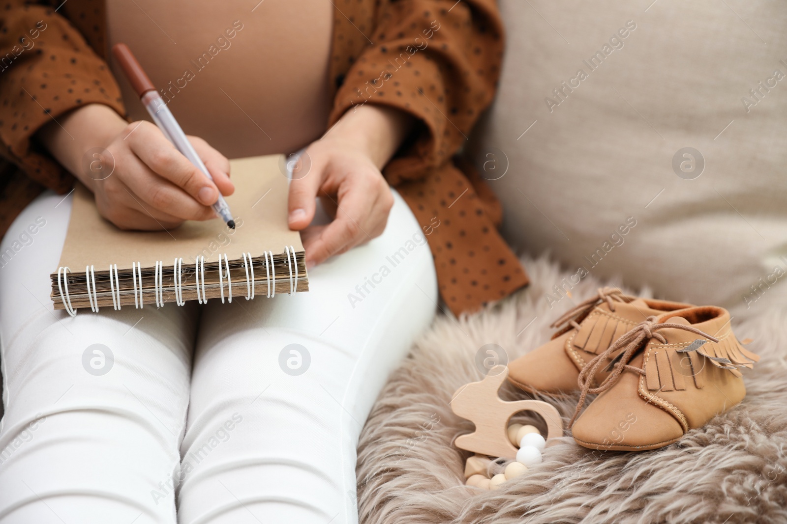 Photo of Pregnant woman writing baby names list at home, closeup