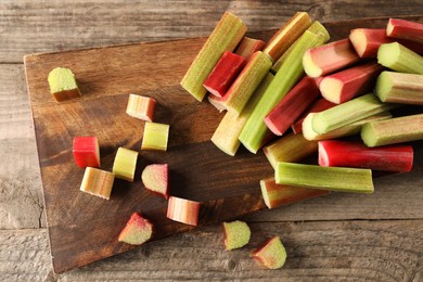 Many cut rhubarb stalks on wooden table, flat lay