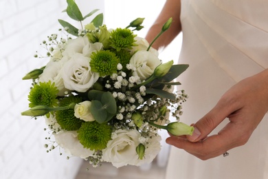 Photo of Bride holding beautiful bouquet with Eustoma flowers indoors, closeup