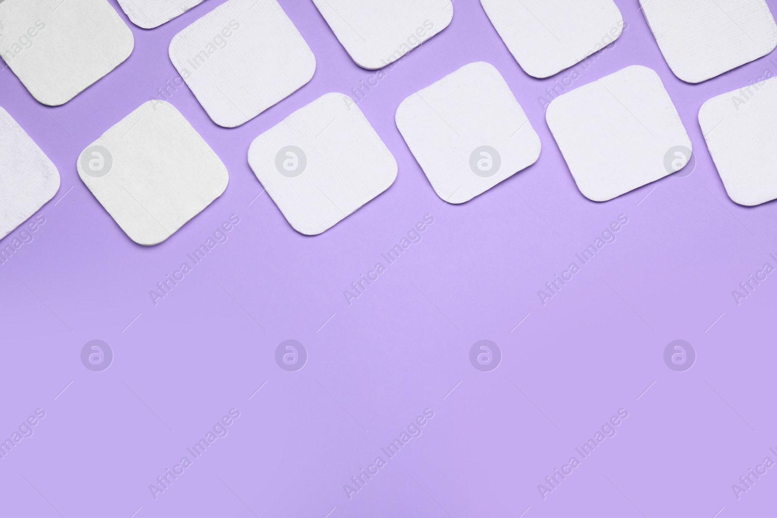 Photo of Many cotton pads on lilac background, flat lay. Space for text