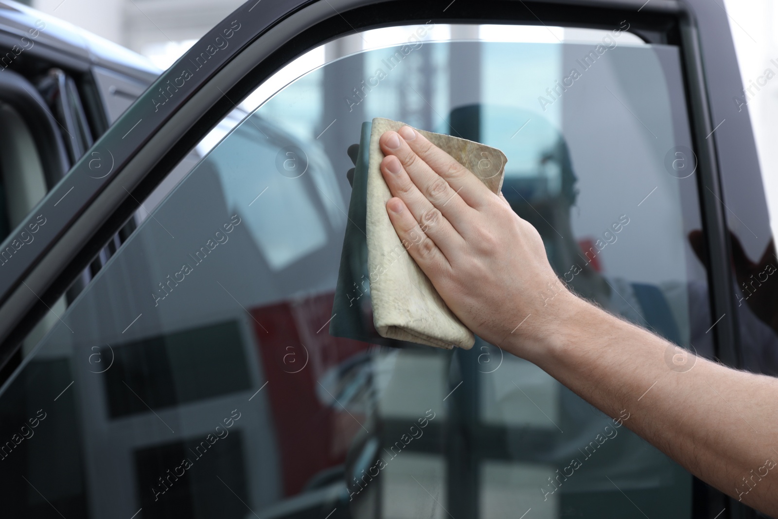 Photo of Worker tinting car window with foil in workshop, closeup