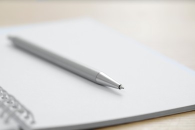 Photo of Open notebook with pen on wooden table, closeup