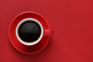 Photo of Cup with aromatic coffee on red background, top view. Space for text