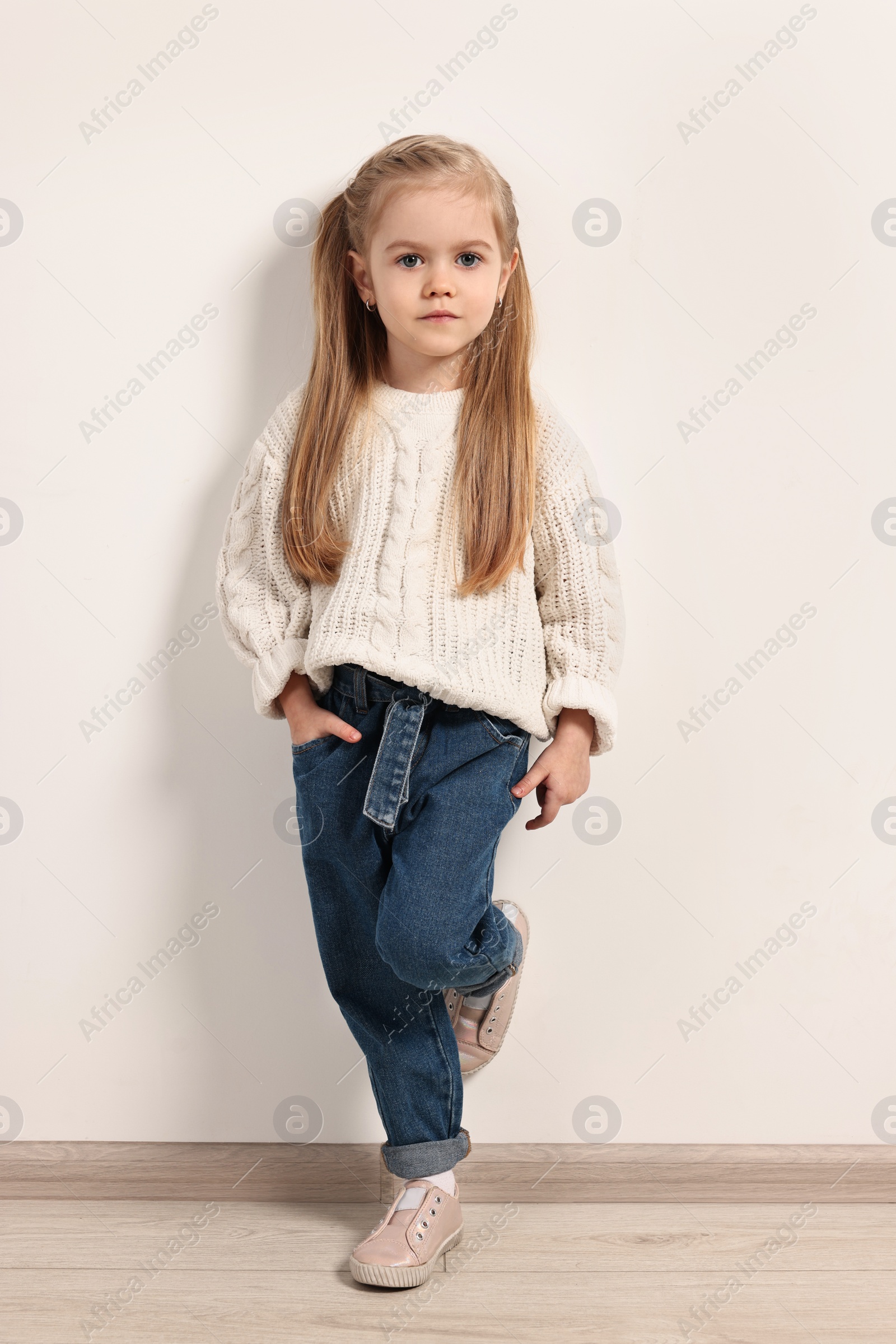 Photo of Fashion concept. Stylish girl posing near white wall