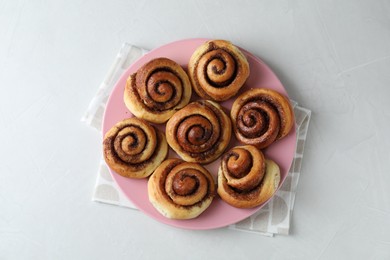 Many tasty cinnamon rolls on white table, top view