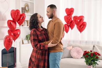 Photo of Lovely couple in room decorated with heart shaped air balloons. Valentine's day celebration