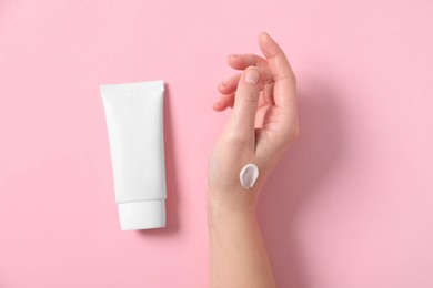 Photo of Woman with tube of hand cream on pink background, top view