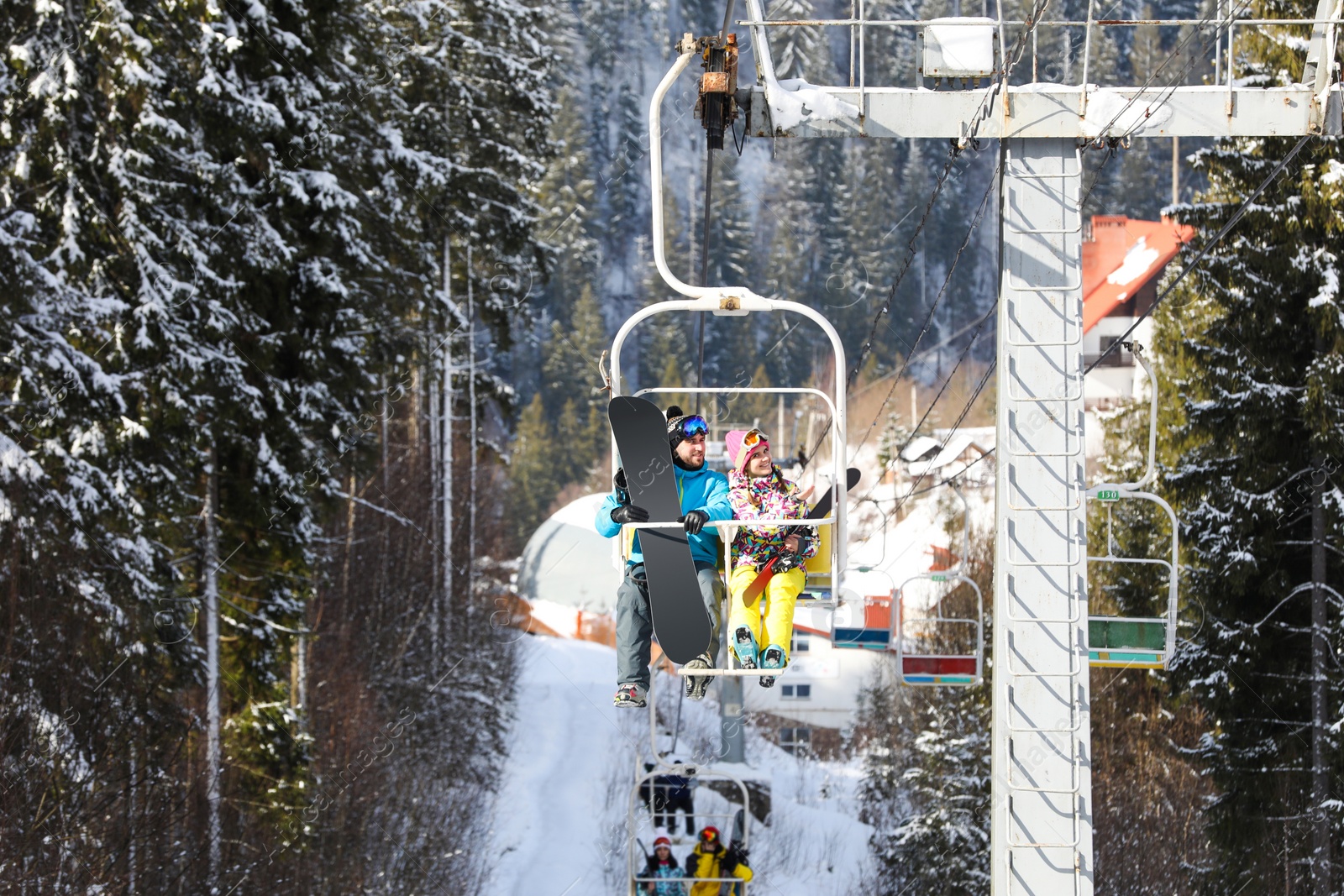 Photo of Couple using chairlift at mountain ski resort. Winter vacation