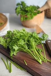 Wooden board with fresh green parsley on table