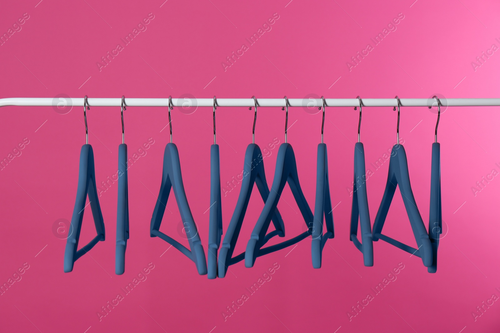 Photo of Metal rack with clothes hangers on color background