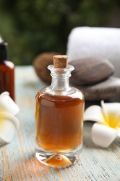 Photo of Composition with spa cosmetic and plumeria flowers on light wooden table, closeup