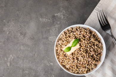 Tasty buckwheat porridge with butter on grey table, flat lay. Space for text