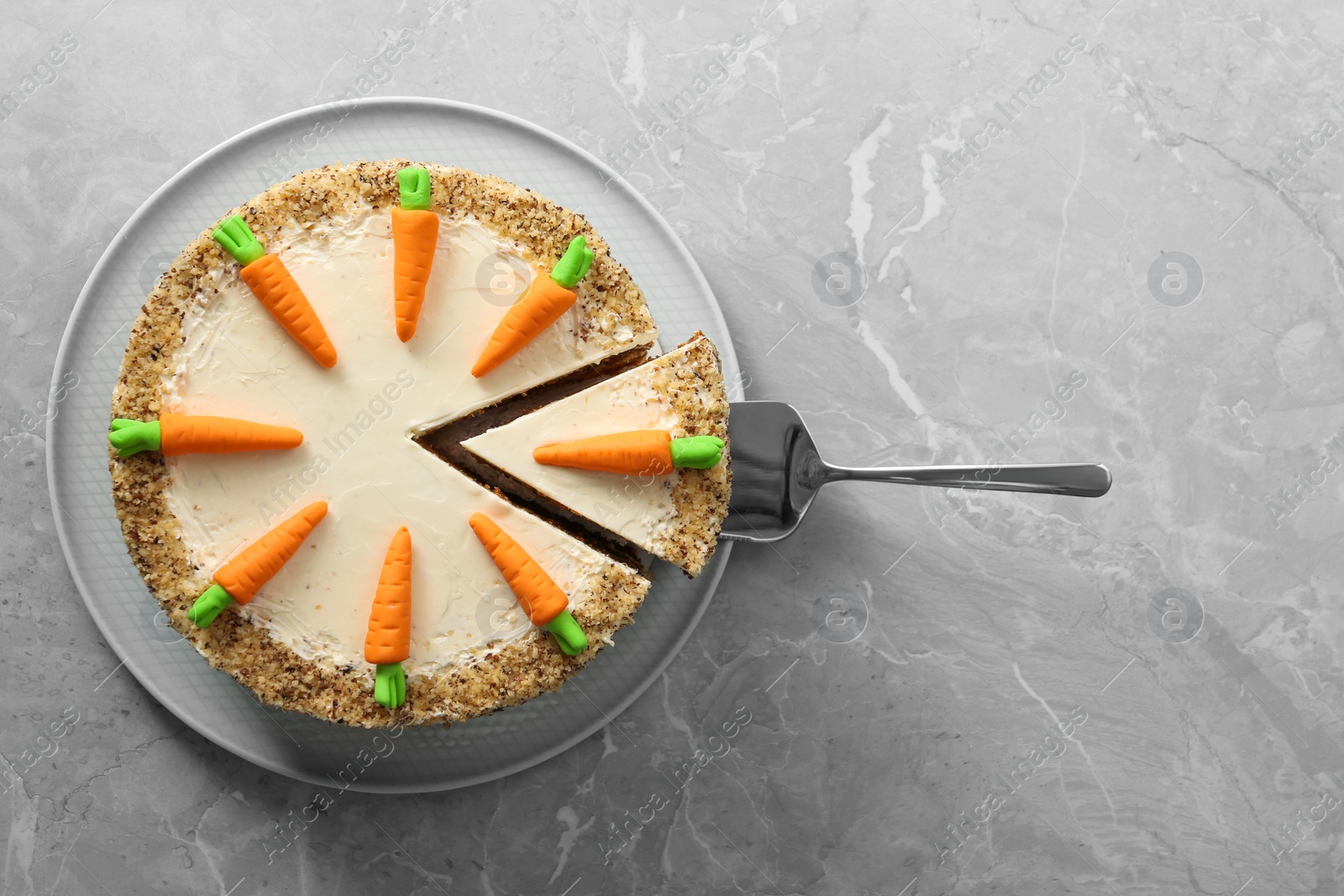 Photo of Sweet carrot cake with delicious cream and server on grey marble table, top view