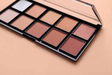 Photo of Colorful contouring palette on beige background, closeup. Professional cosmetic product