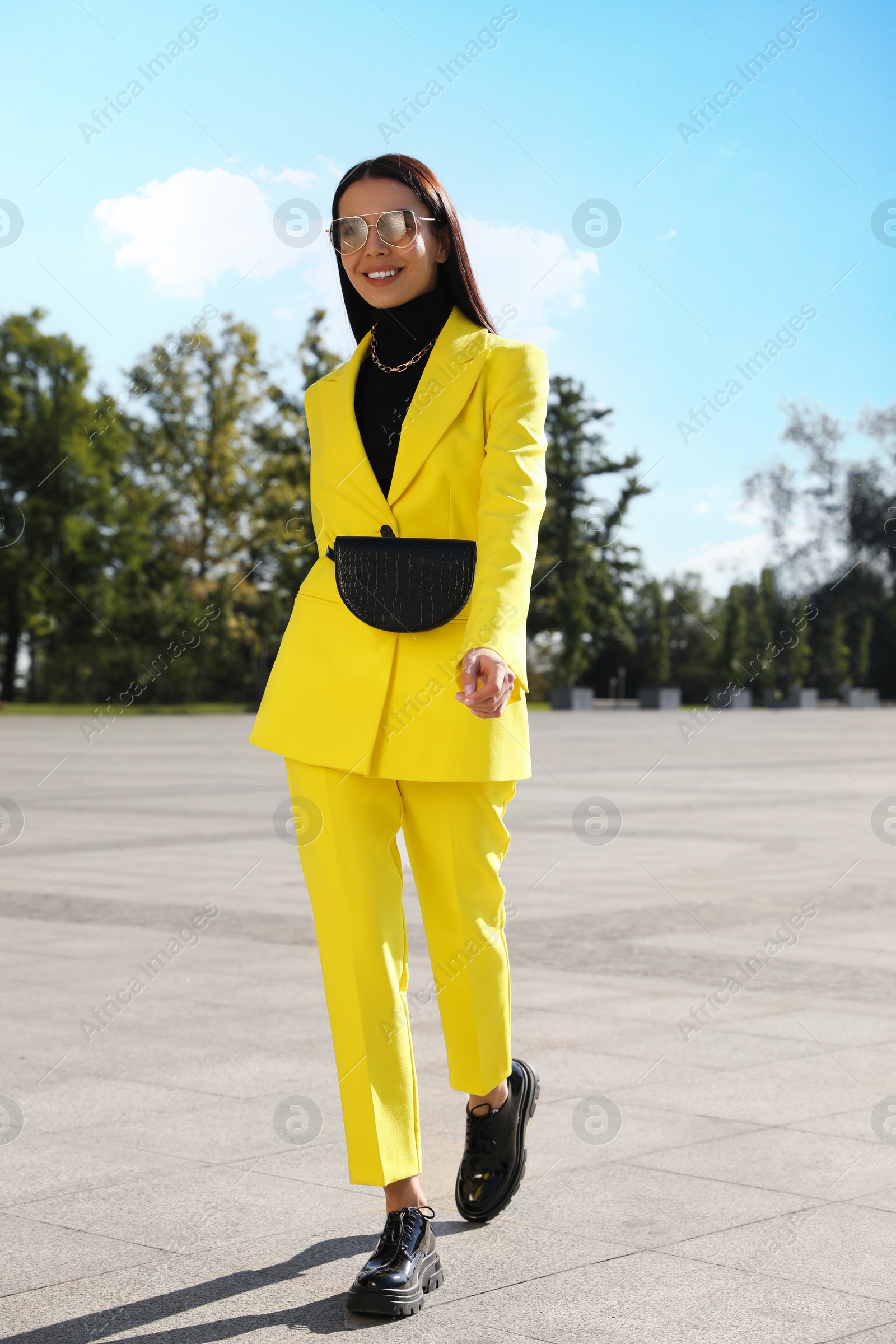 Photo of Beautiful young woman with stylish waist bag on city street