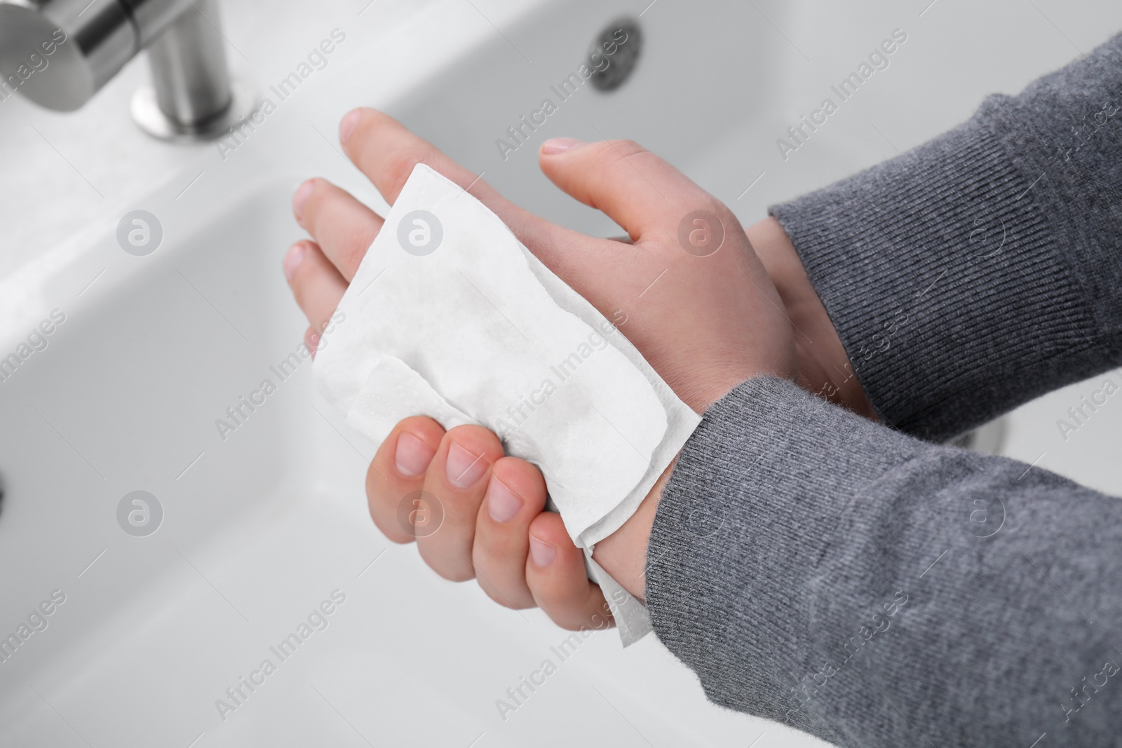 Photo of Man wiping hands with paper towel near sink, closeup