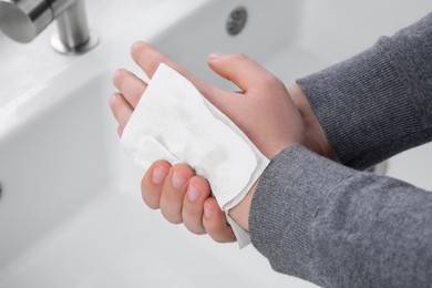 Photo of Man wiping hands with paper towel near sink, closeup