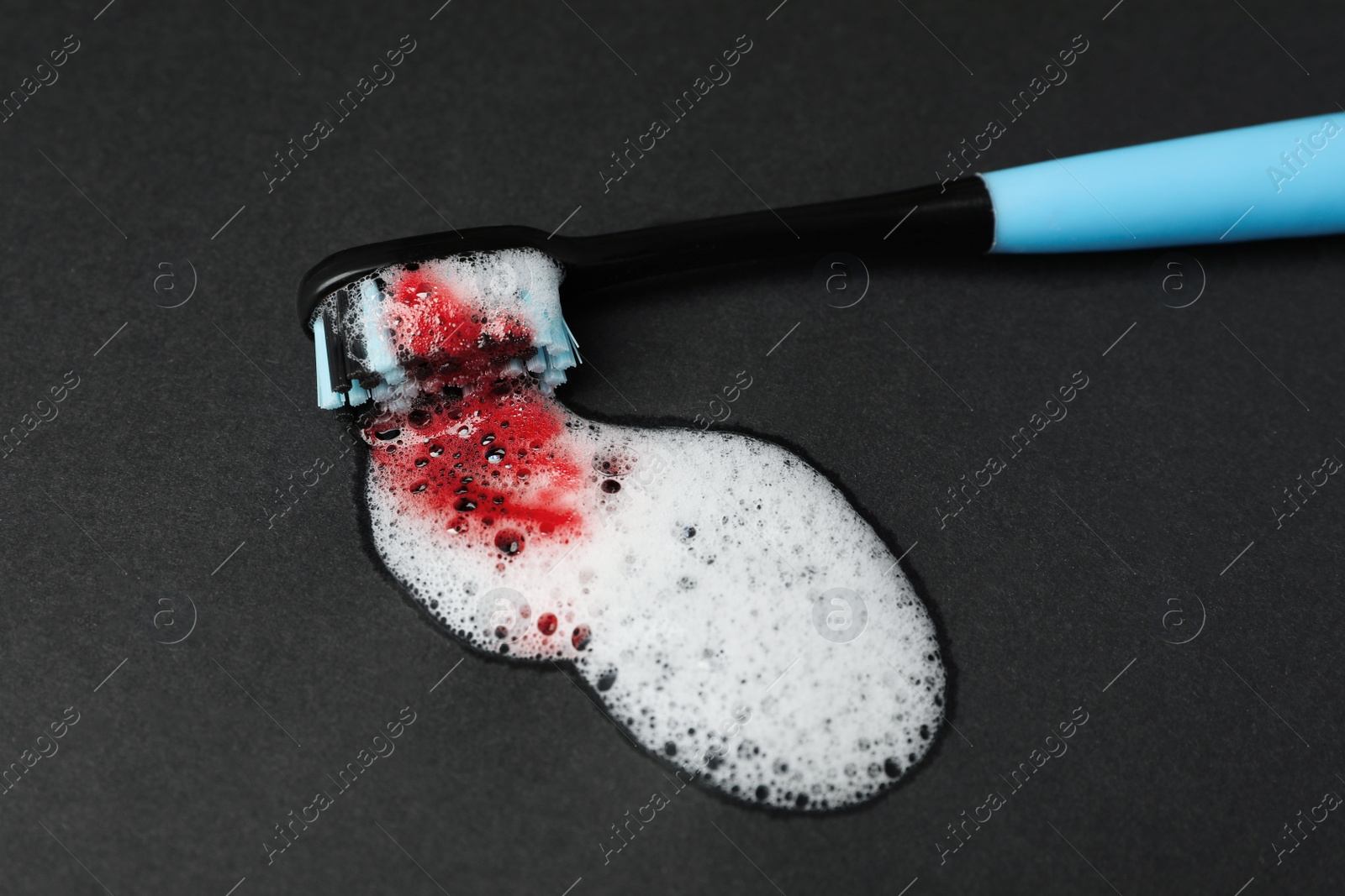 Photo of Toothbrush with paste and blood on black background, closeup. Gum inflammation