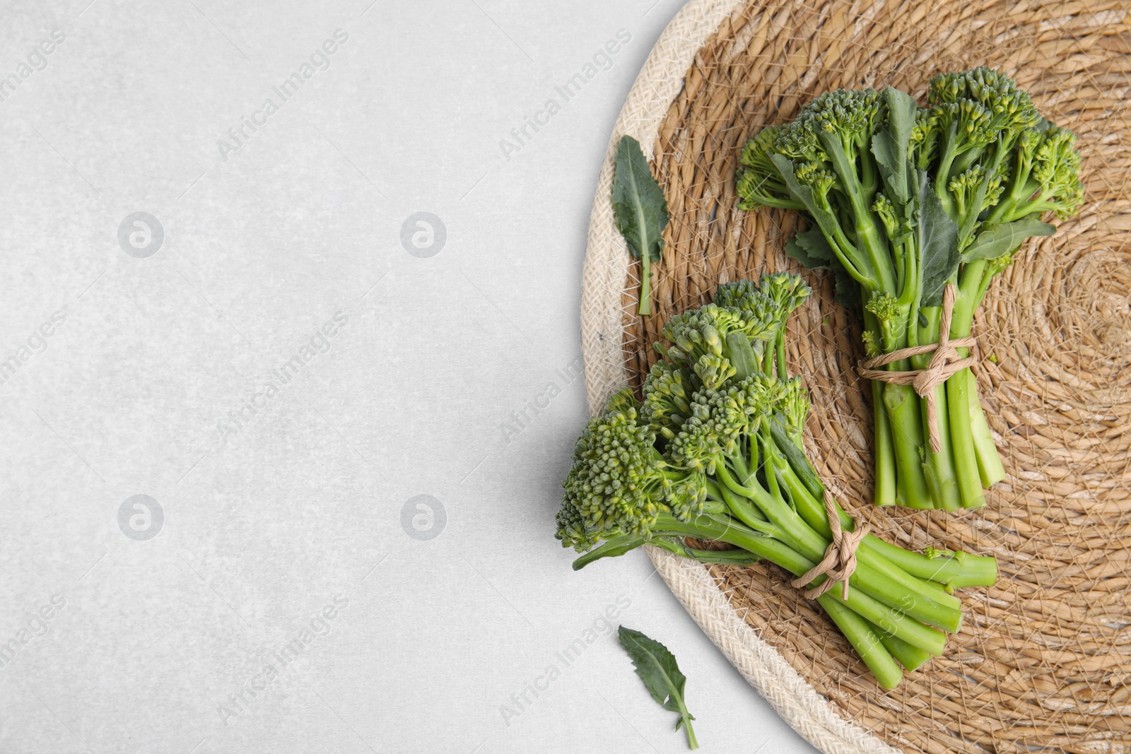 Photo of Fresh raw broccolini on white table, top view and space for text. Healthy food