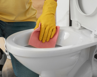 Man cleaning toilet bowl in bathroom, closeup