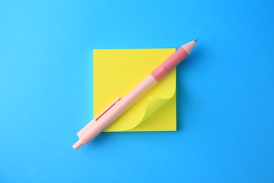 Photo of Blank paper note and pen on light blue background, top view