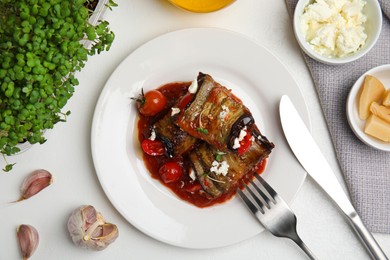 Tasty eggplant rolls served on white table, flat lay