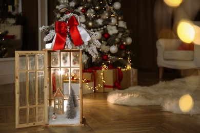 Beautiful lantern with festive composition near Christmas tree indoors