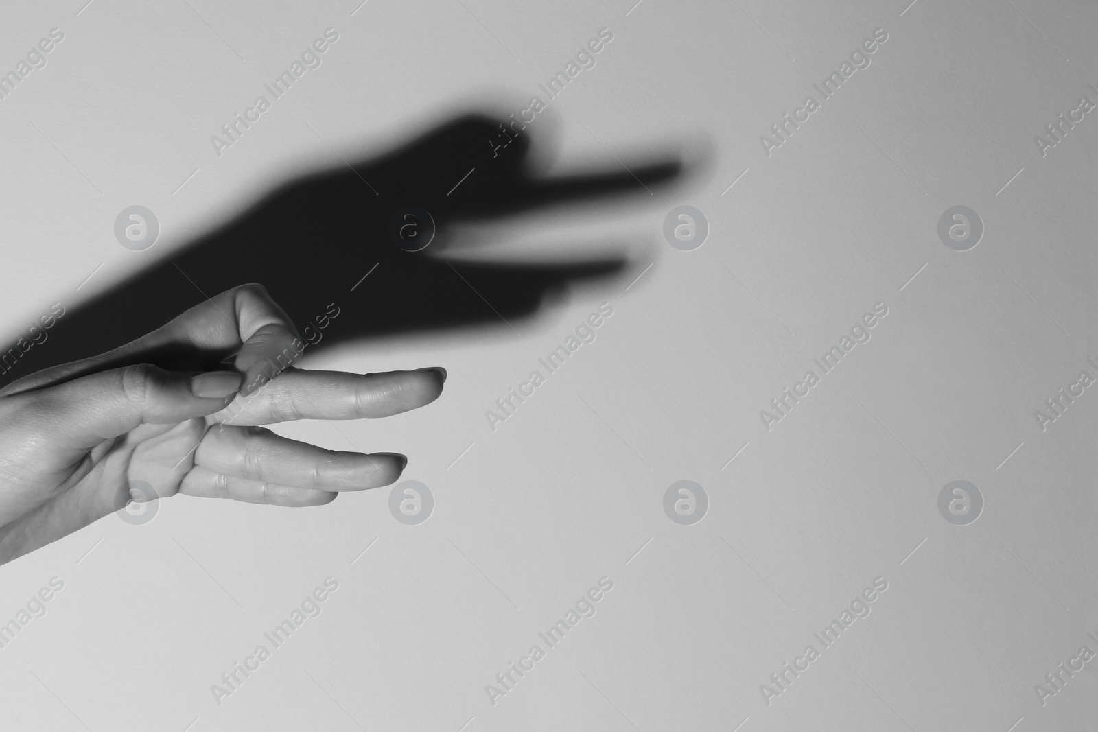 Photo of Shadow puppet. Woman making hand gesture like goose on light background, closeup with space for text. Black and white effect