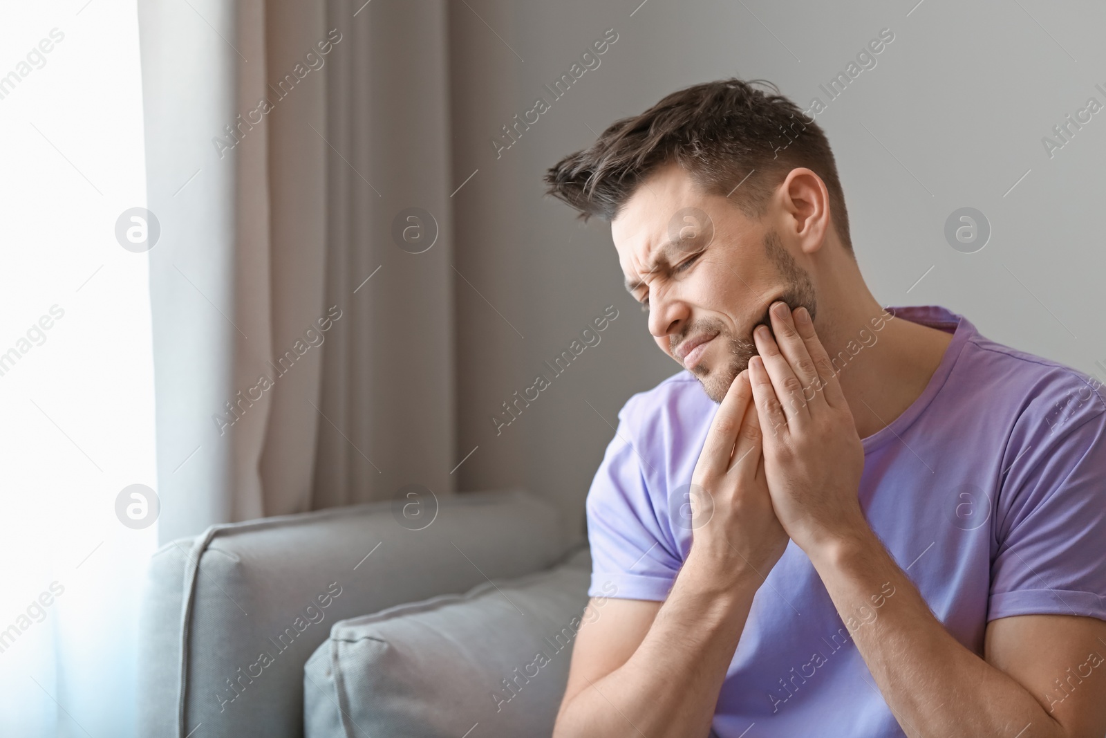 Photo of Young man suffering from toothache at home