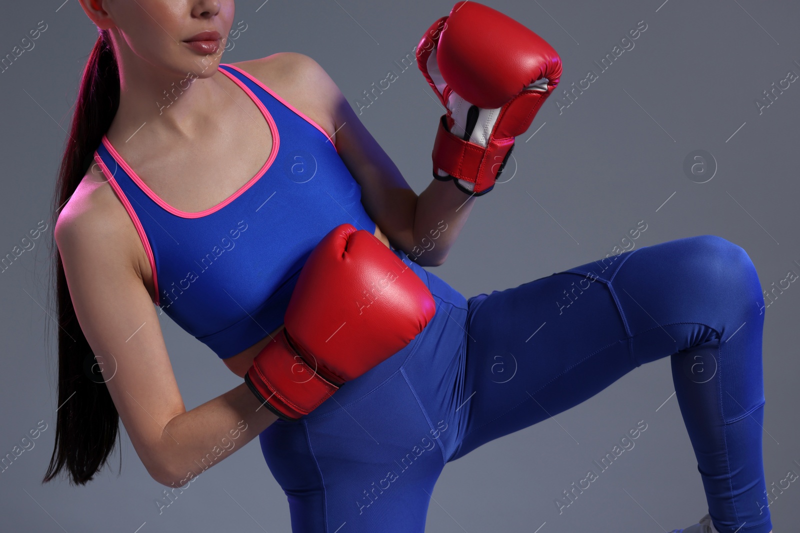 Photo of Woman in boxing gloves on grey background, closeup