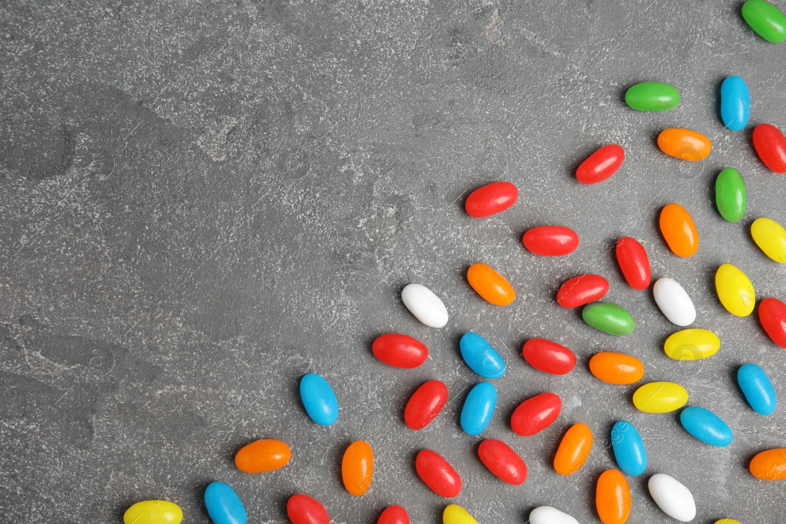 Photo of Flat lay composition with jelly beans on stone background. Space for text