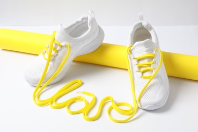 Photo of Stylish sneakers and word Love made with yellow shoe laces on white background